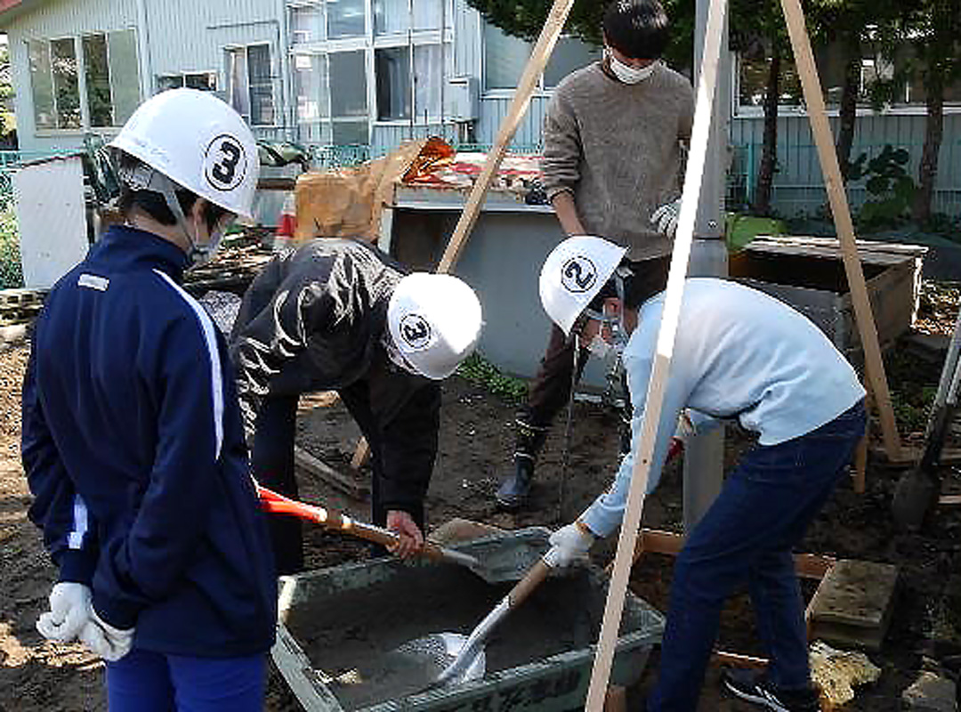 中学生をサポートする学生(風力発電装置の取付)