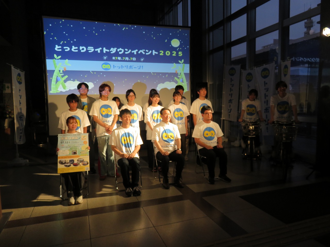 学生2名が自転車を漕いで自家発電した光を使って記念撮影